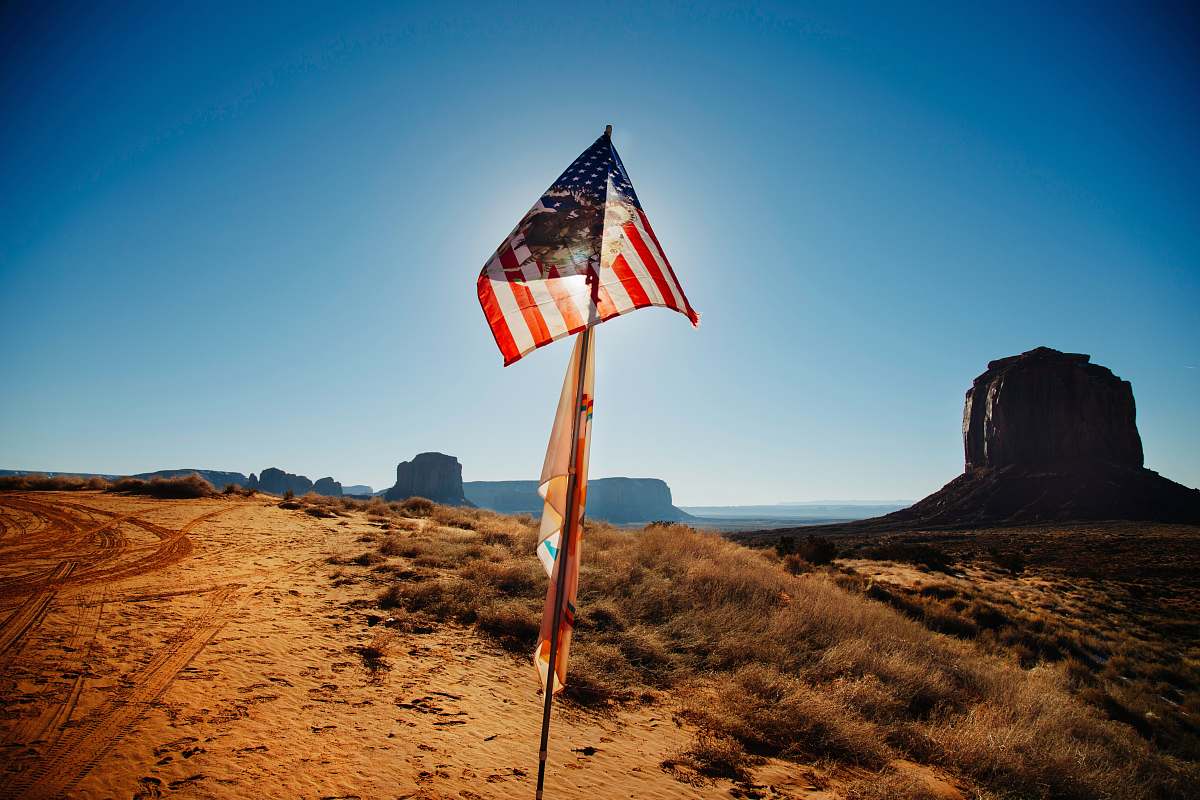 desert USA flag waving over brown sand outdoors